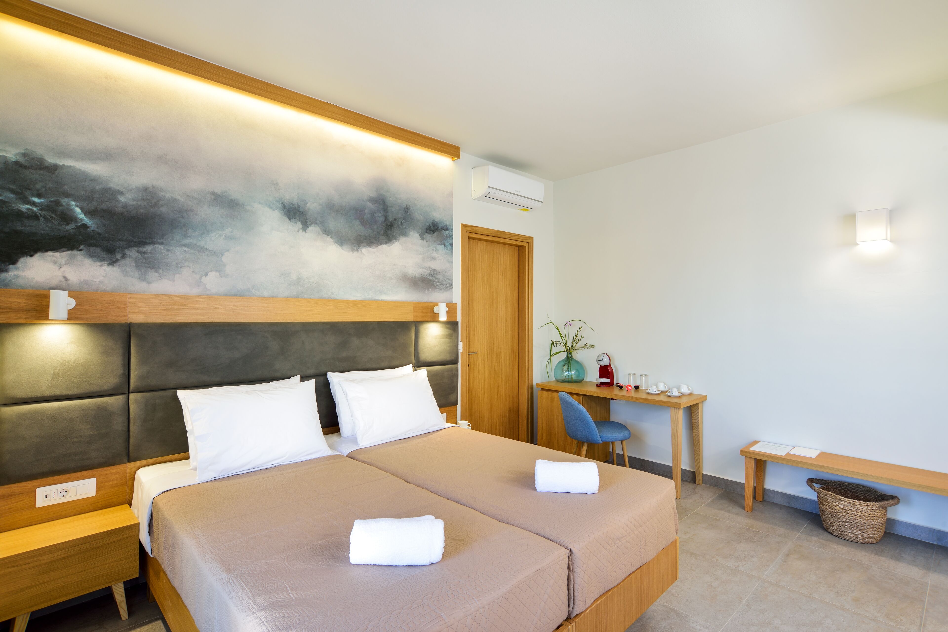 A hotel room with a bed, bedside tables, a desk, and a chair.