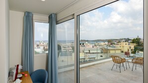 A balcony with a city view, a table with chairs, and a window with curtains.