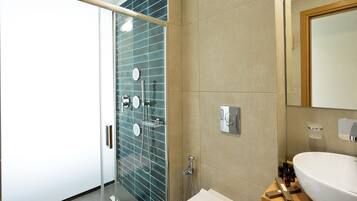 Un baño moderno con cabina de ducha de vidrio, un lavamanos grande y un espejo.