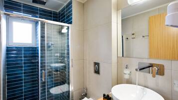 A modern bathroom with a glass-enclosed shower, a white sink, and a wooden vanity.