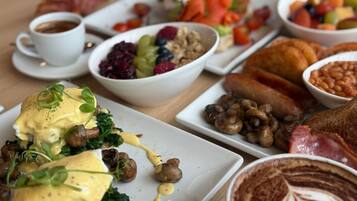 Un buffet de petit-déjeuner proposant divers plats, notamment des œufs, des champignons et des haricots.