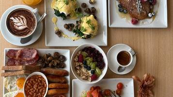 A breakfast spread with various dishes and drinks on a wooden table.