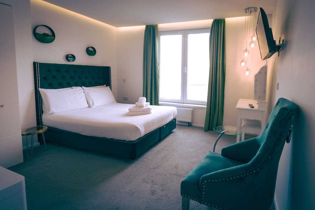 Ein Hotelzimmer mit Bett, Stuhl, Schreibtisch und einem Fenster mit Vorhängen.