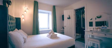 A hotel room with a neatly made bed, a desk with a chair, a bathroom with a shower, and a large window with curtains.