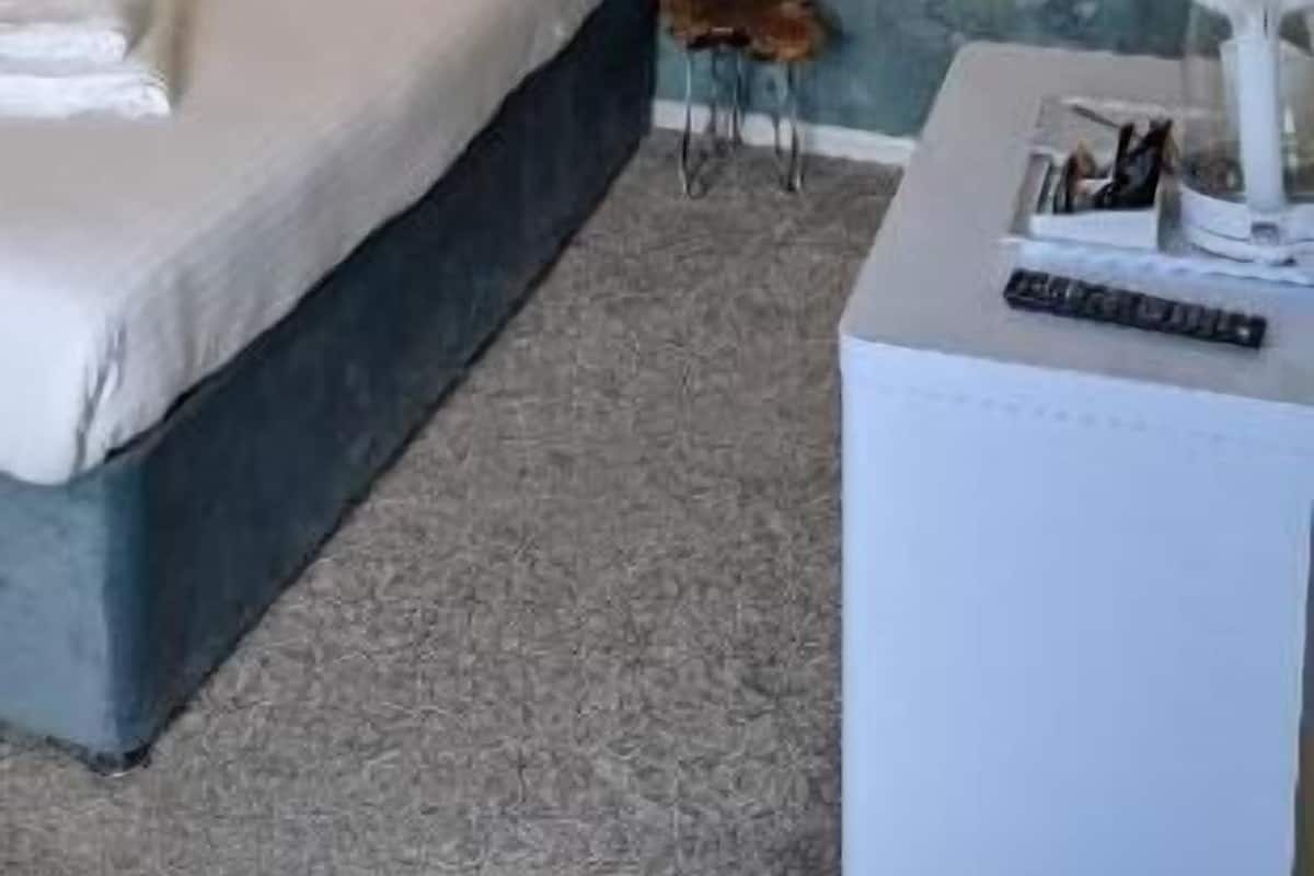 Ein Schlafzimmer mit einem Bett, einem kleinen Nachttisch, einem Sessel und einem an der Wand montierten Fernseher.
