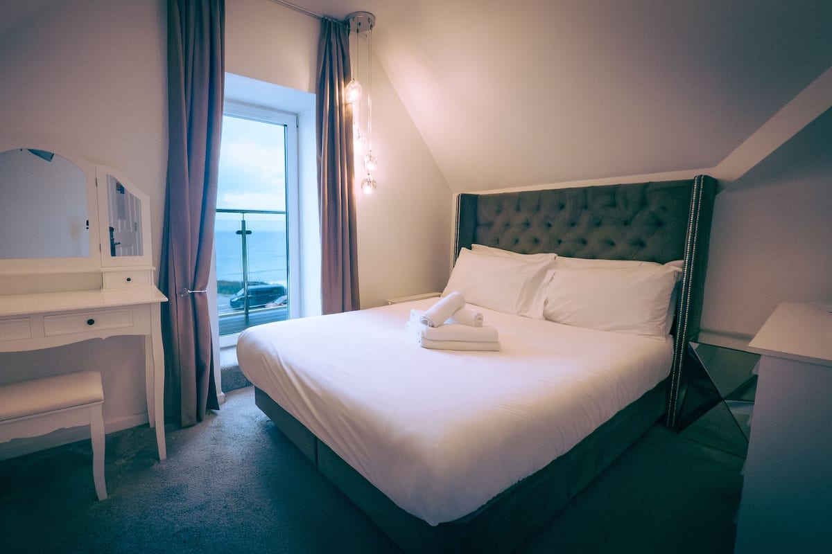 Ein Hotelzimmer mit Bett, Schreibtisch, Stuhl, Spiegel und einem Fenster mit Vorhängen.