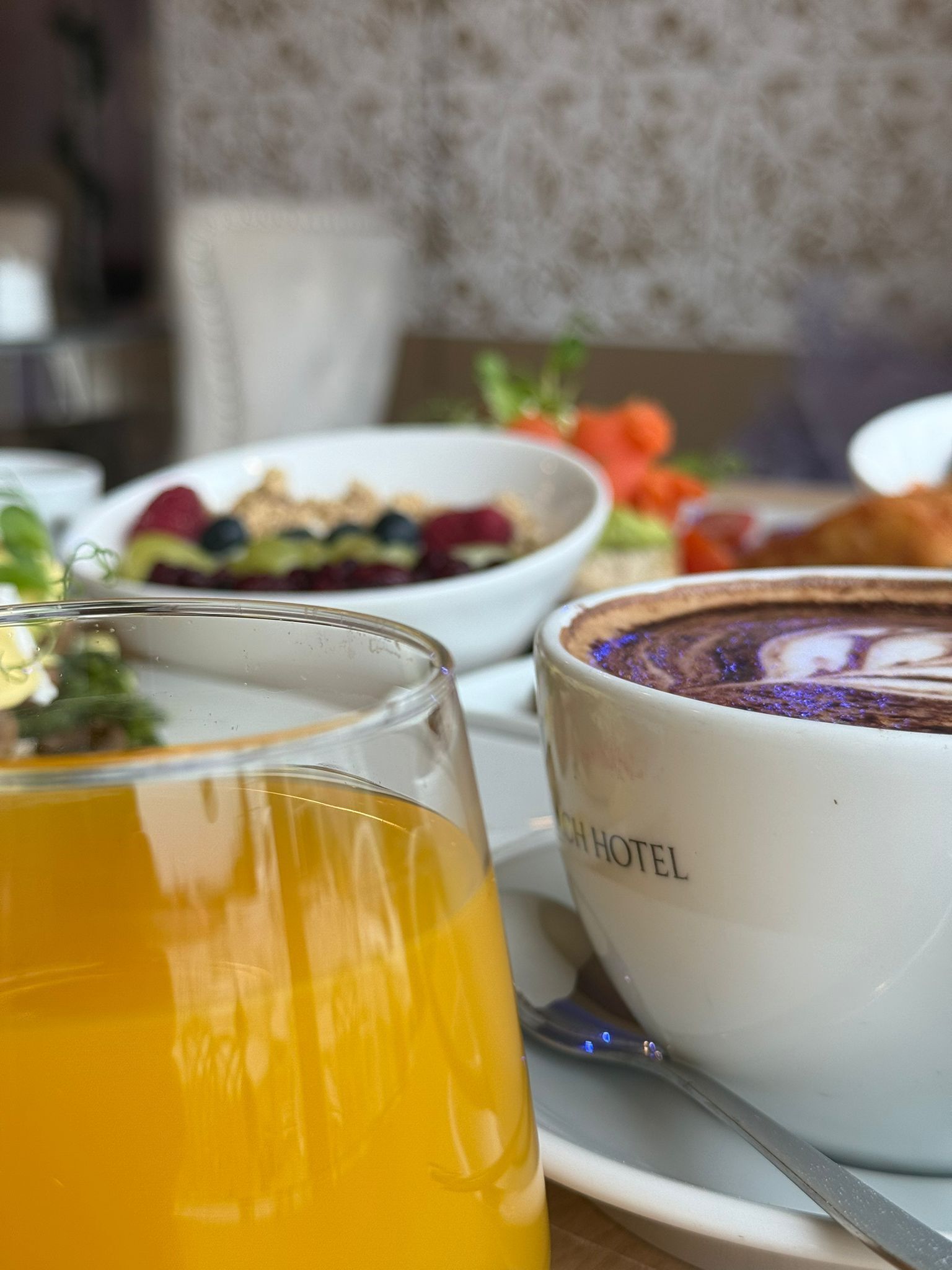 A breakfast setting with a glass of orange juice, a bowl of cereal with fruits, and a cup of coffee.