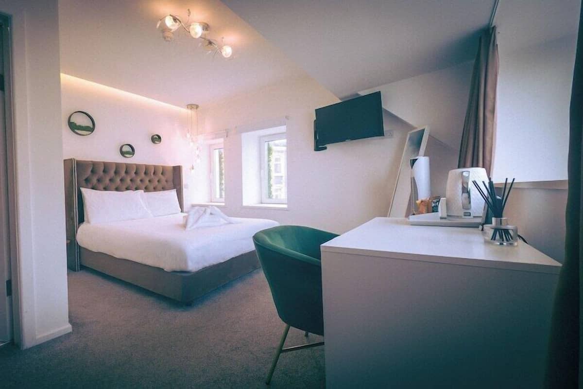 Ein Schlafzimmer mit Bett, Schreibtisch, Stuhl, Flachbildfernseher und Fenster.