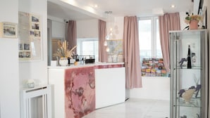 Een moderne keuken met een marmeren aanrecht, een groot raam met gordijnen, en een verzameling boeken en souvenirs.