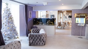 Een moderne woonkamer met een kerstboom, een groot aquarium en een bord met daarop een restaurant.