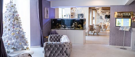 Un salon moderne avec un sapin de Noël, un grand aquarium et une enseigne de restaurant.