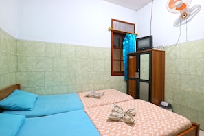 A room with two beds, a TV, a fan, and a window with curtains. - Hotel Setia Budi (Malang)