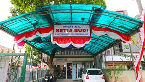 Entrada de hotel com uma placa indicando 'HOTEL SETIA BUDI' e um número de contato.