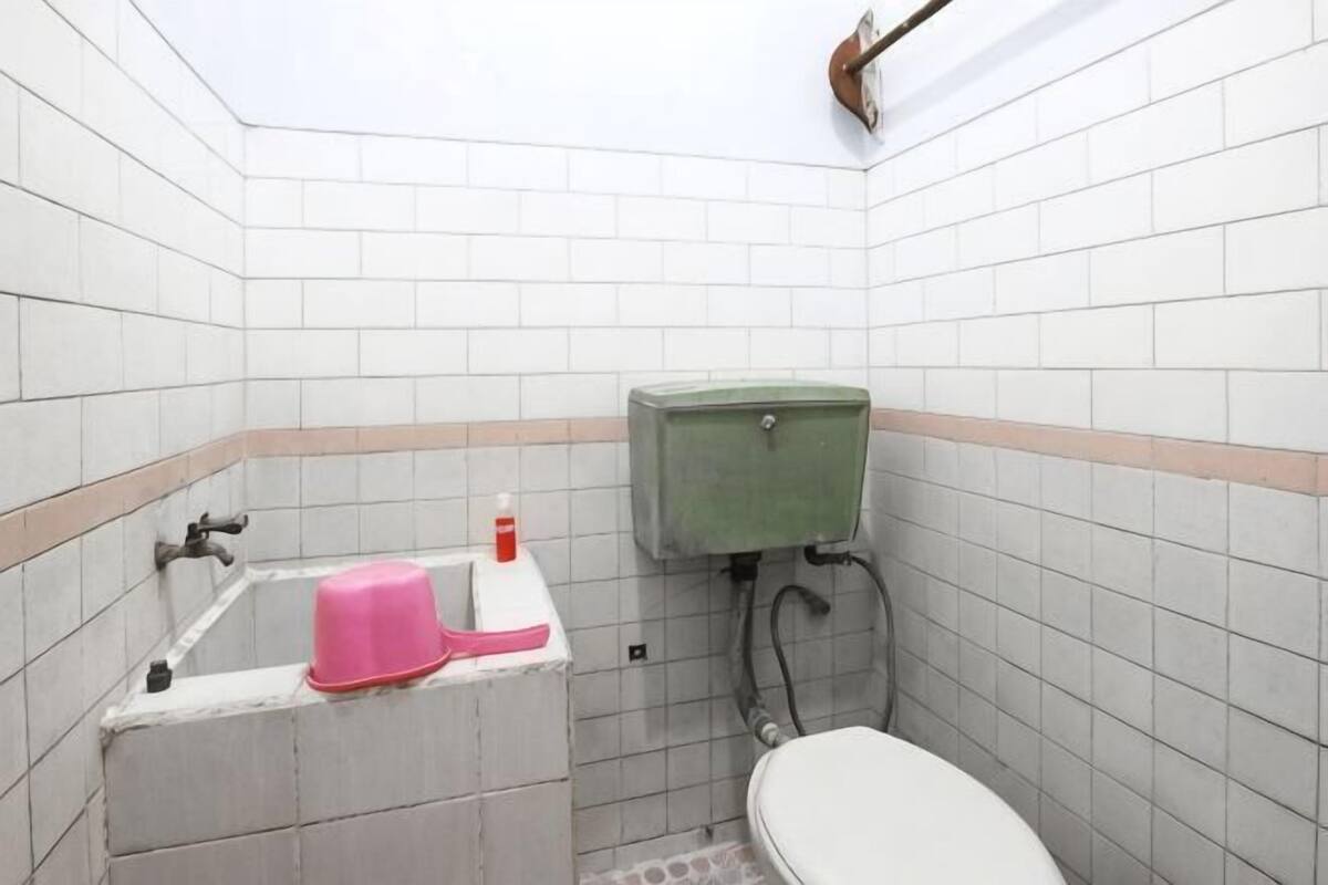 A small bathroom with a toilet, a sink with a pink soap dish, and a green toilet tank.