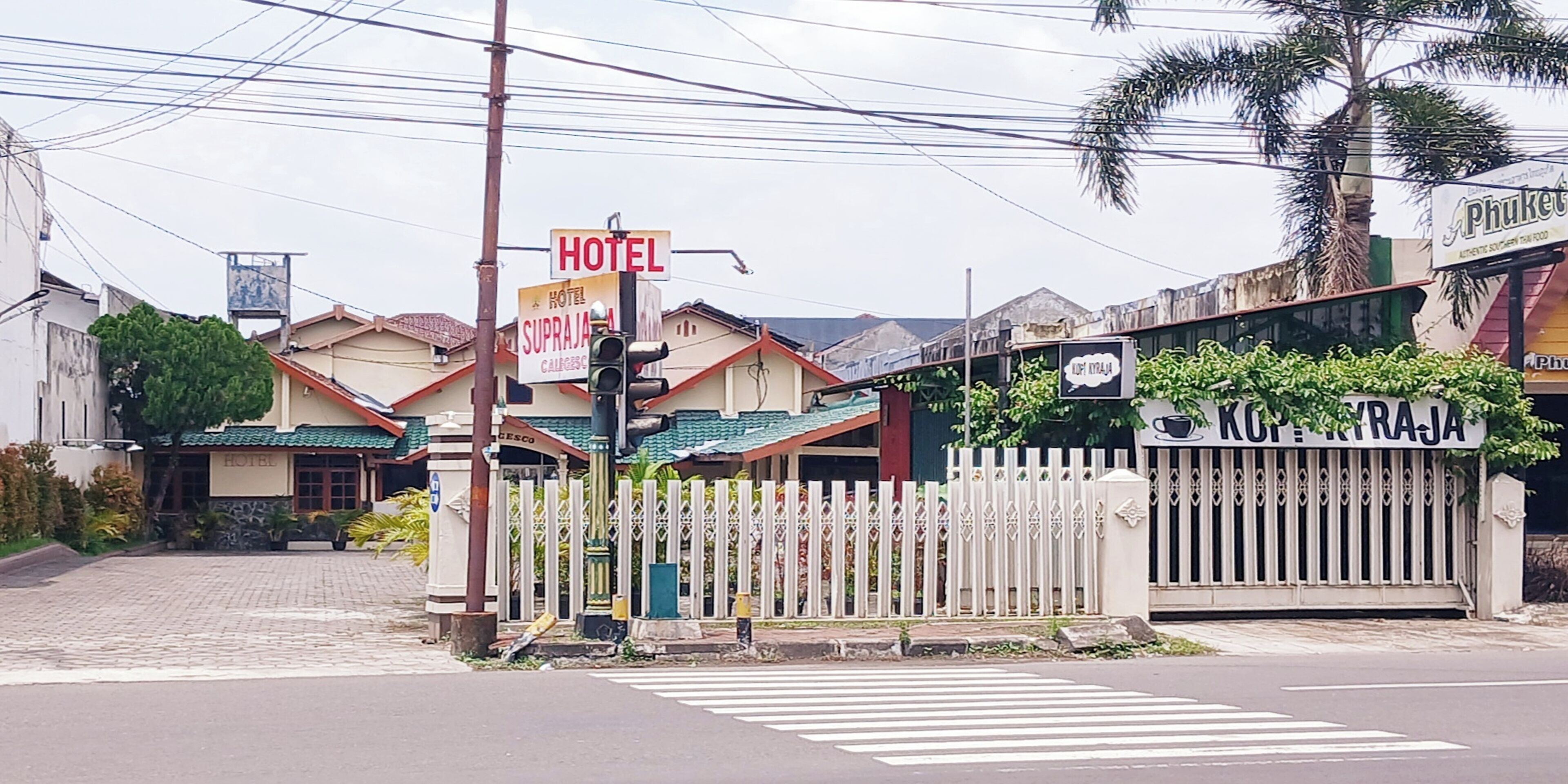 Un hotel con letrero, entrada porticada y camino de acceso pavimentado.