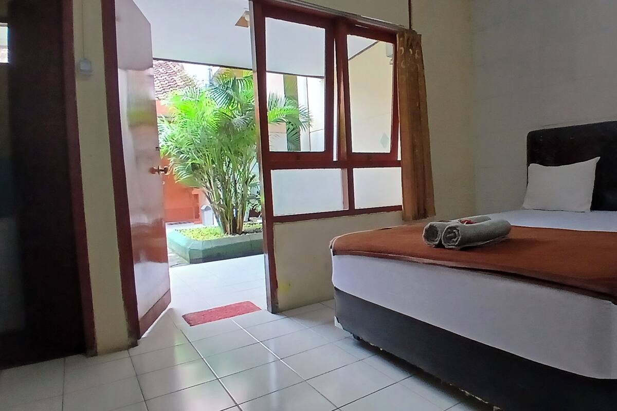 Un dormitorio con una cama, una ventana y vistas al verdor exterior.