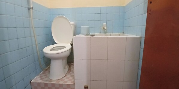 A bathroom with a toilet, sink, and blue tiled walls. - Hotel Supra Jaya (Yogyakarta)