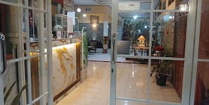 Un vestíbulo de hotel con mostrador de recepción, zona de estar y una pared decorativa.