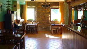 A dining area with a stone wall, wooden furniture, and a chandelier. - Hotel Rural Huelde (Cremenes)
