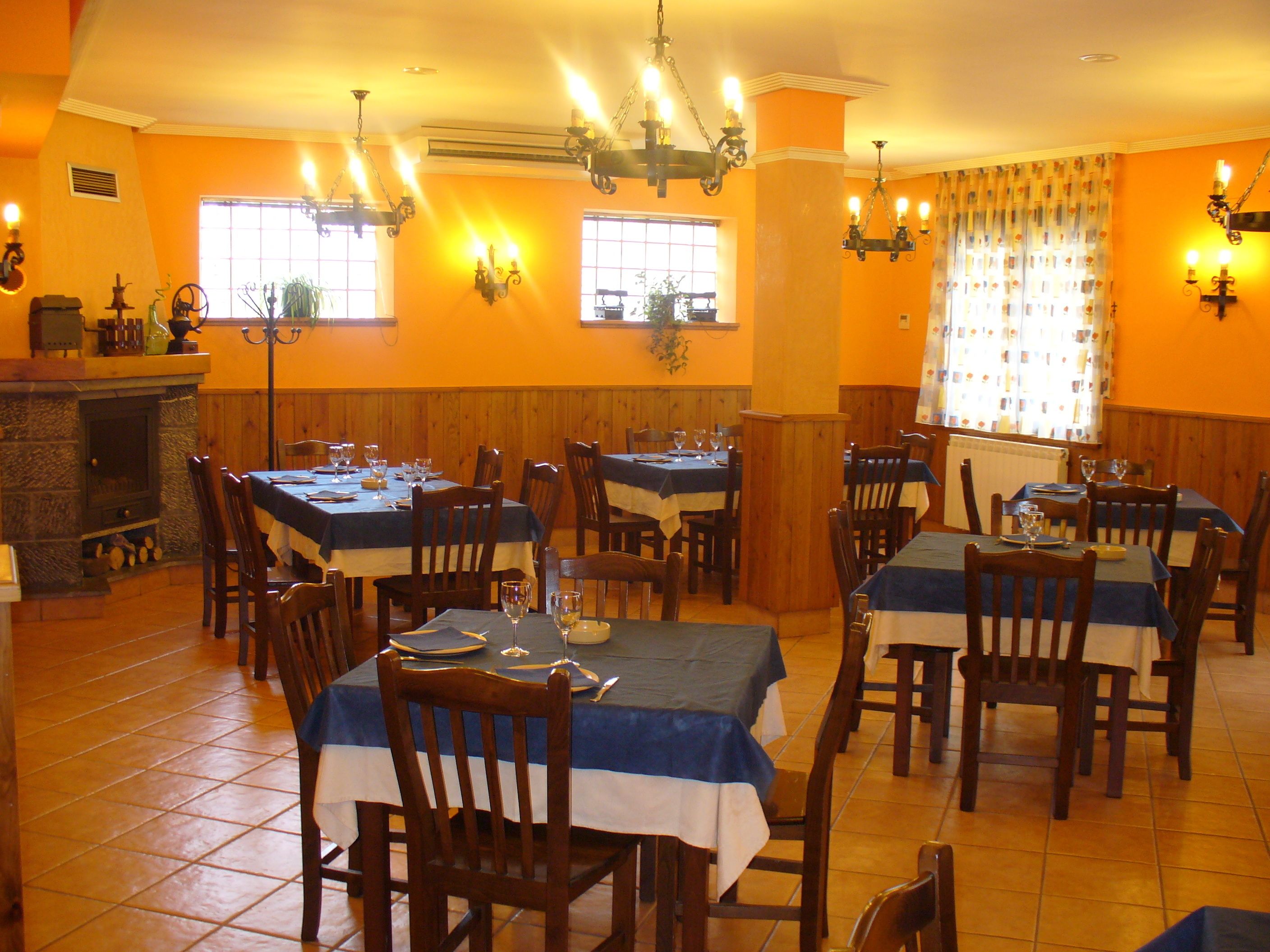 Ein Restaurant mit mehreren Tischen und Stühlen, einem Kamin und dekorativen Wandleuchten.