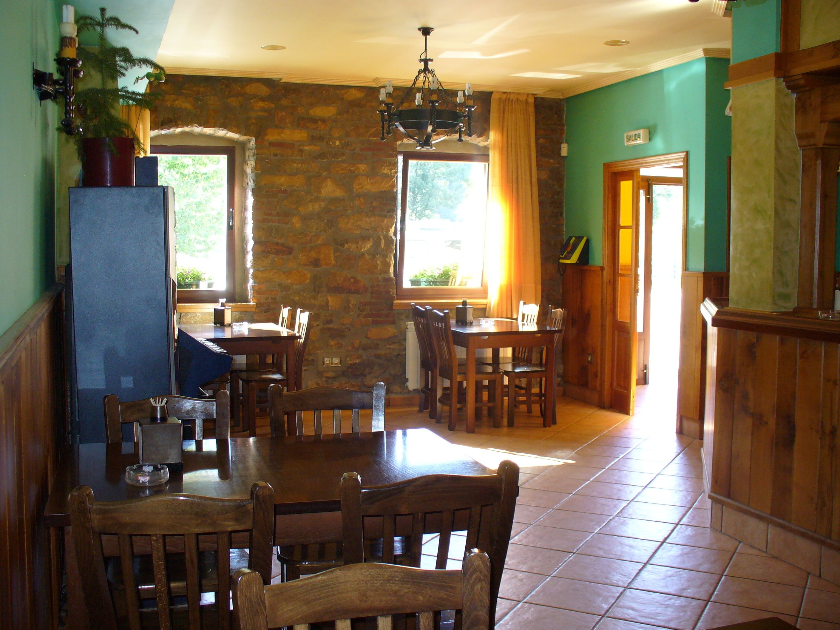 Un comedor con pared de piedra, muebles de madera y una araña.