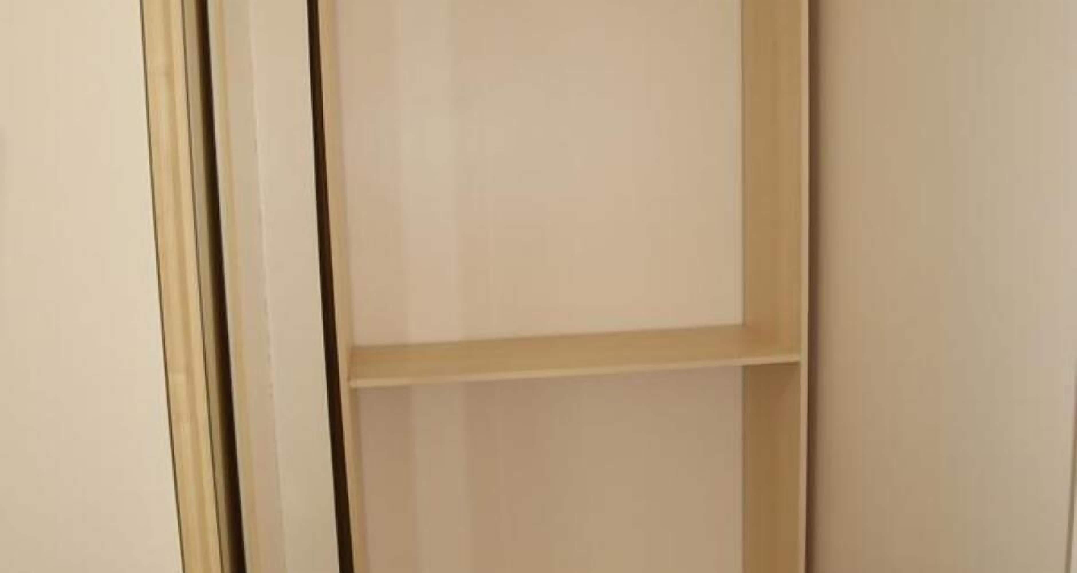 A view of a room with a wooden door and a light-colored wall.