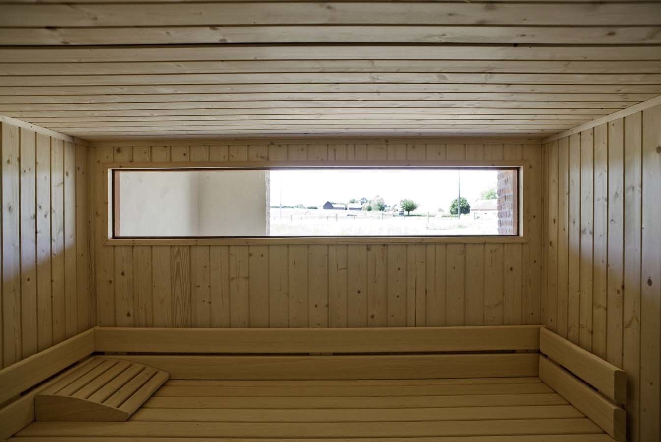 A wooden sauna room with a bench and a large window.