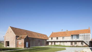 A large brick barn with a sloped roof and a modern extension with large windows.