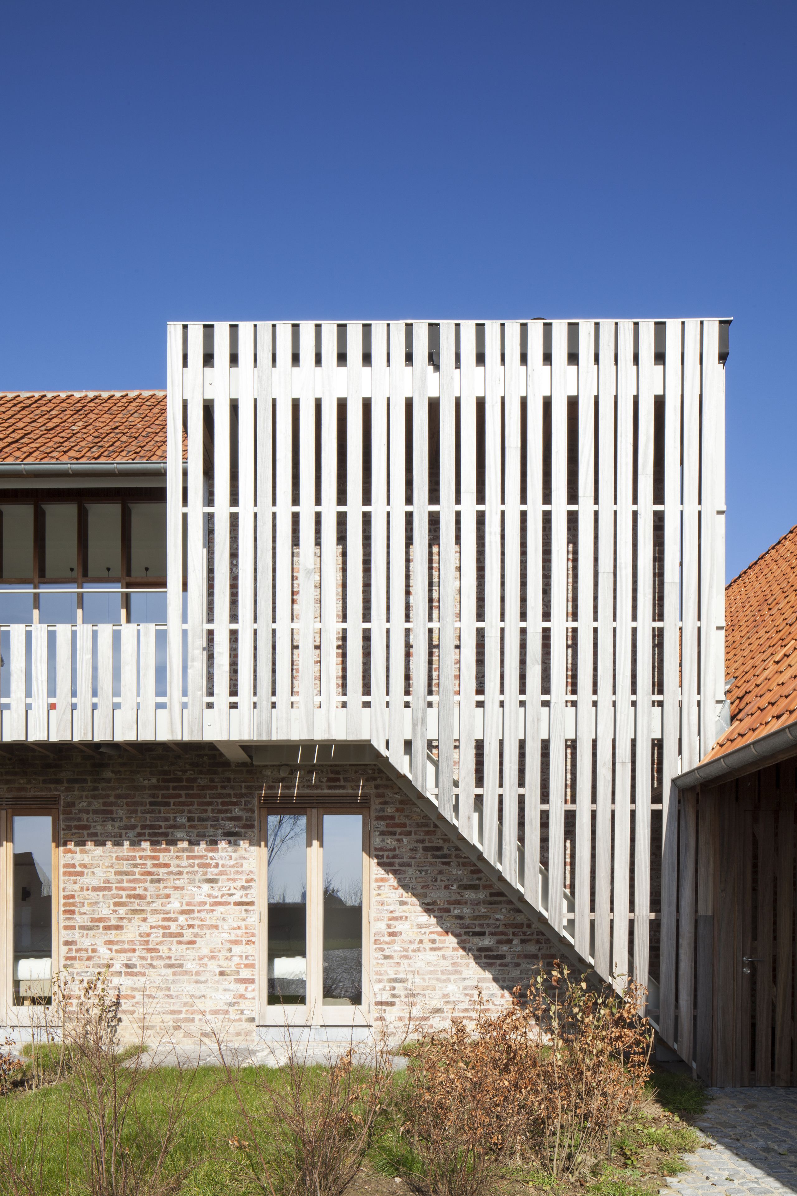 Un edificio moderno con facciata in mattoni e struttura in legno bianco con listelli verticali.