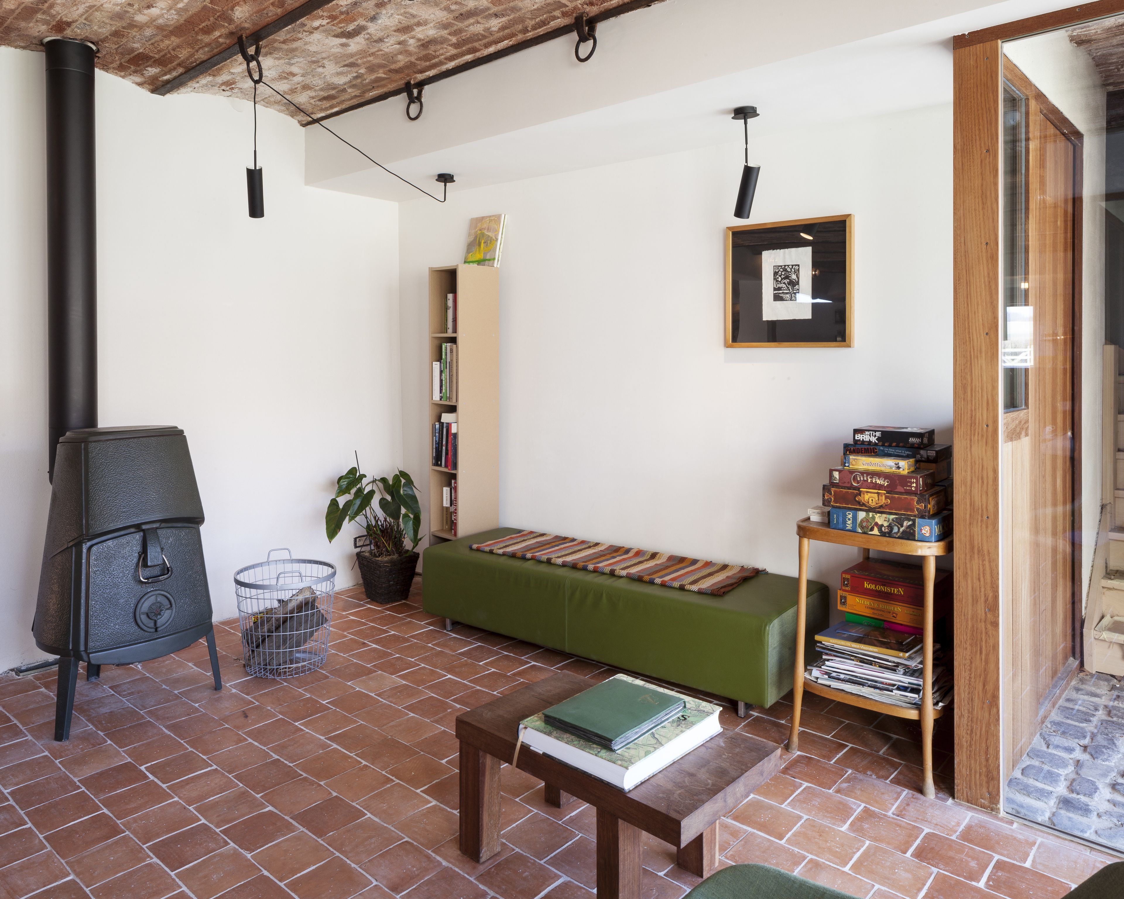 Una sala de estar acogedora con un sofá verde, una mesa de centro de madera, una estantería y una chimenea.