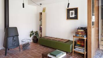A cozy living room with a green sofa, a wooden coffee table, a bookshelf, and a fireplace.