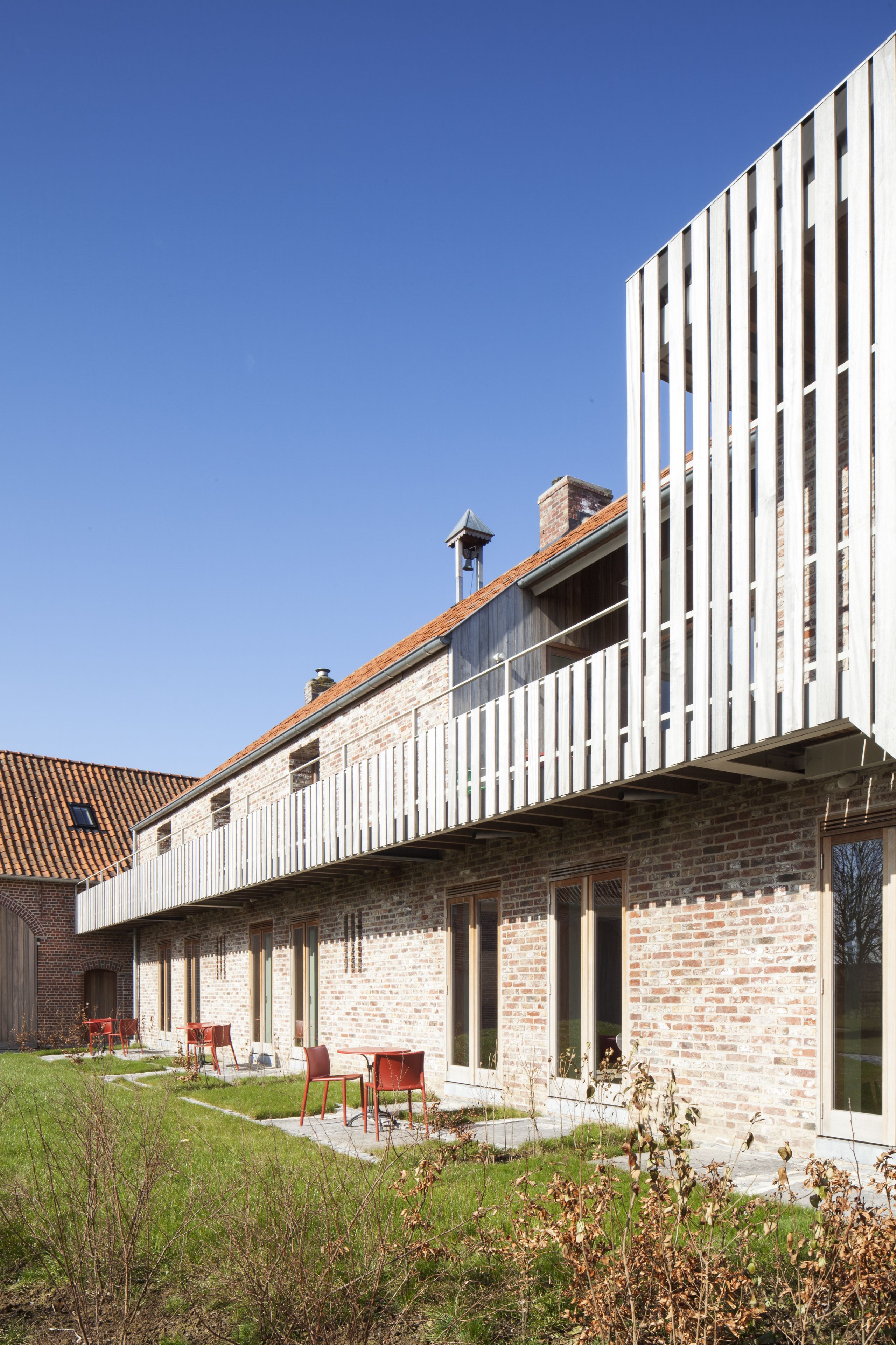 A modern building with a brick facade, large windows, and a flat roof.