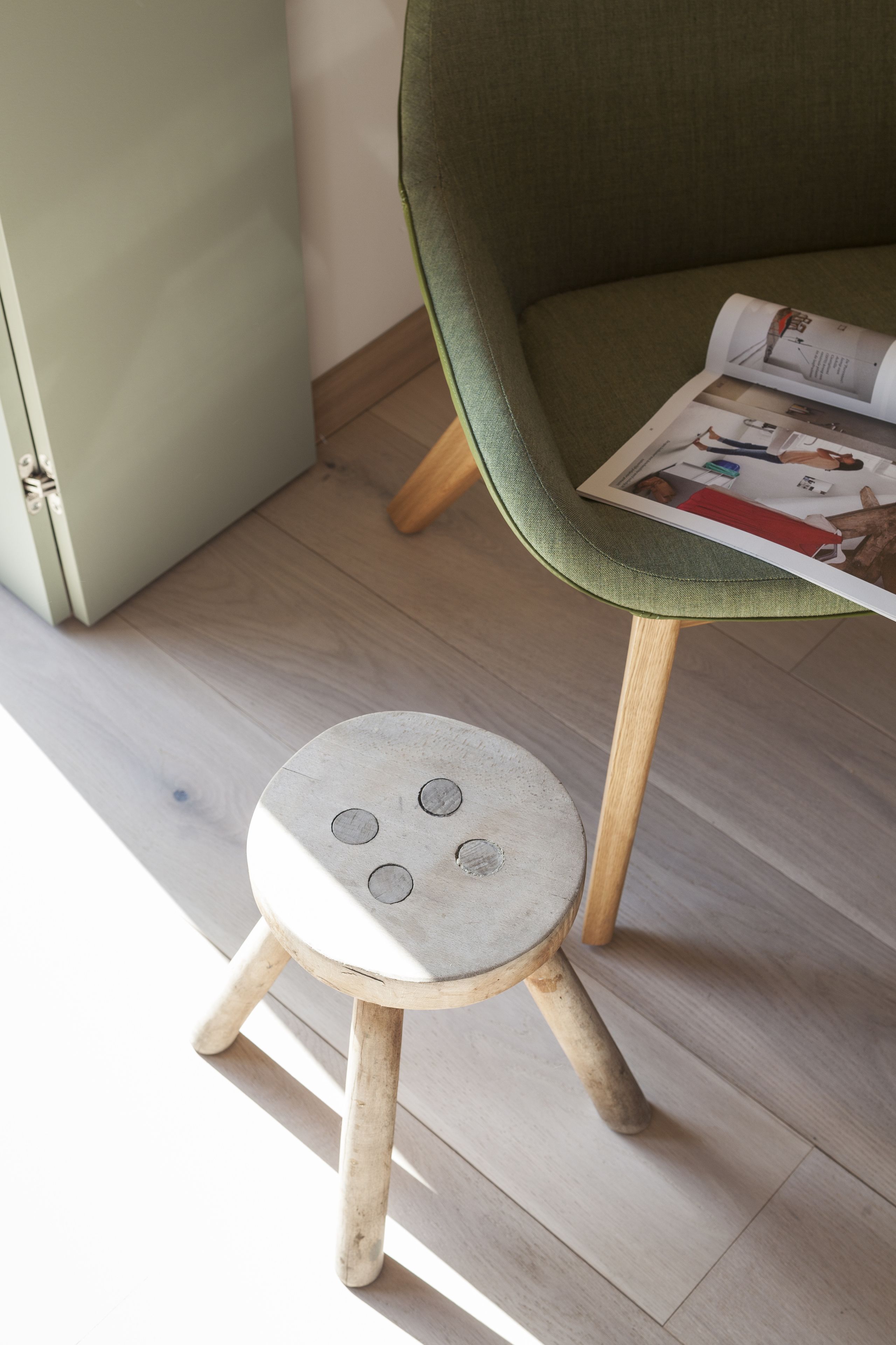 A small stool with a round seat and four legs, placed on a light-colored wooden floor.