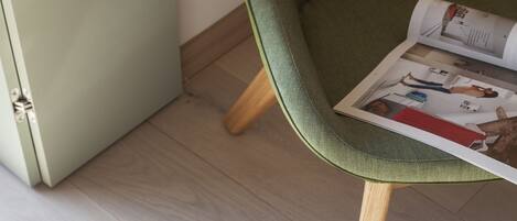 A small stool with a round seat and four legs, placed on a light-colored wooden floor.