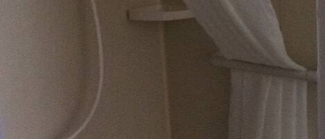 A bathroom with a shower curtain, a toilet, and a wall-mounted hand dryer.