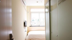 Une chambre à coucher avec un lit, une fenêtre et une armoire.
