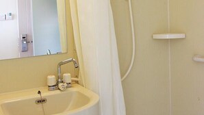 Une salle de bain avec un lavabo, un miroir, une douche et des murs blancs.