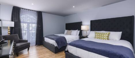 A hotel room with two beds, a desk, and a chair.