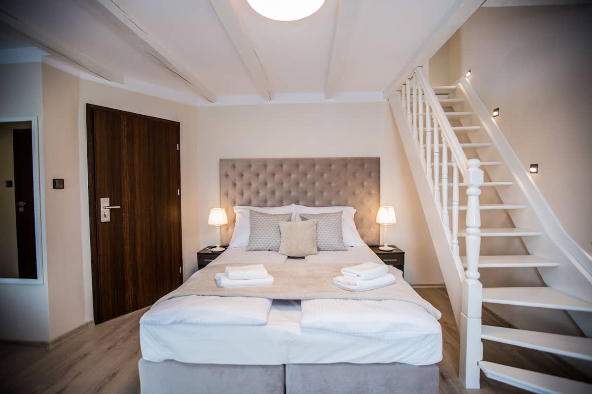 Ein Schlafzimmer mit einem großen Bett, einer Holztür, einer Treppe und zwei Nachttischlampen.