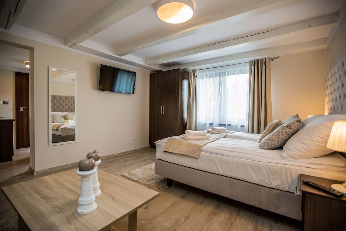 Ein Schlafzimmer mit Bett, Wandfernseher, Holztisch und Spiegel.