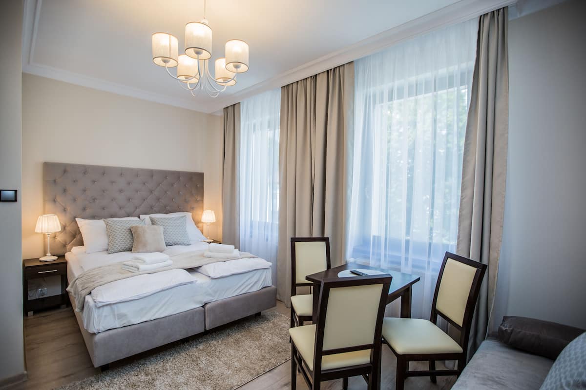 Ein Hotelzimmer mit einem großen Bett, einem Schreibtisch mit Stühlen und einer Kristallleuchtre.