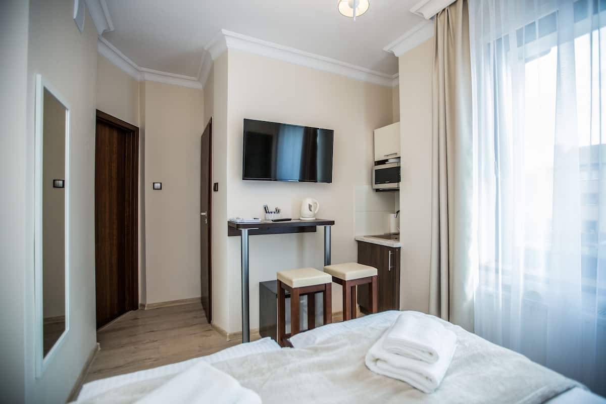 Ein Hotelzimmer mit einem Bett, einem Schreibtisch mit zwei Stühlen, einem Fernseher und einer Küchenzeile.