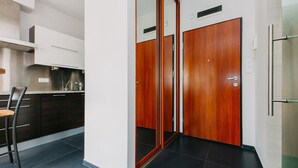 Eine moderne Küche mit dunklen Schränken, einer Edelstahl-Dunstabzugshaube und einer Holztür zu einem Badezimmer.