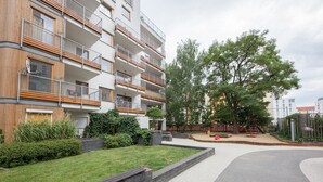 Ein modernes Mehrfamilienhaus mit mehreren Balkonen, einem Spielplatz und einem gepflegten Garten.