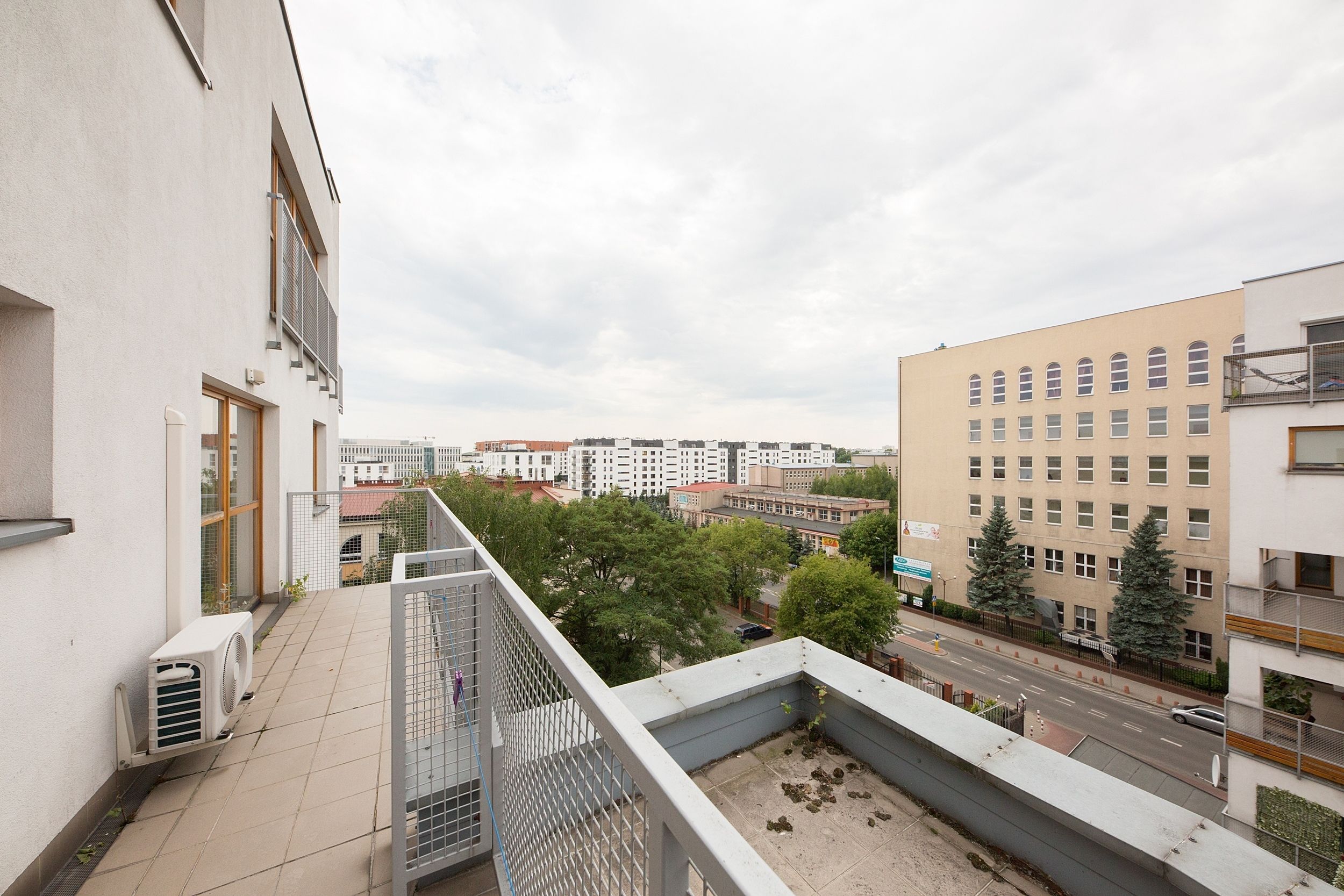 A balcony with a view of a cityscape, including buildings and a road.