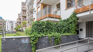 Ein modernes Mehrfamilienhaus mit Balkonen, einer Treppe und einer mit Efeu bewachsenen Backsteingemäuer.