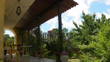 Un espacio al aire libre cubierto con techo de madera, sillas amarillas y plantas en macetas.