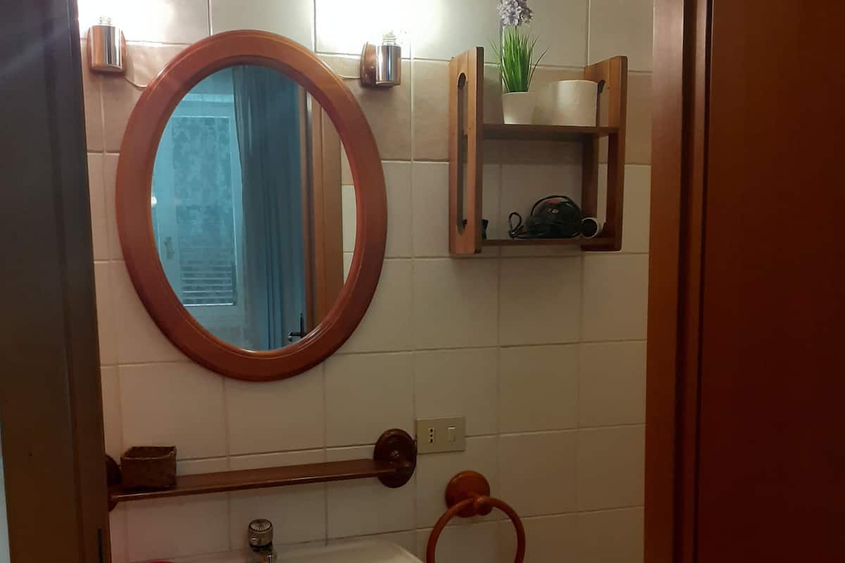Ein Badezimmer mit einem weißen Waschbecken, einem Spiegel, einer kleinen Ablage mit Toilettenartikeln und einer Toilette.