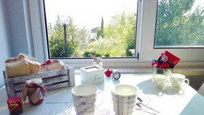 Une table donnant sur les arbres à l’extérieur, une boîte étiquetée « Thé », ainsi que différentes tasses et un pot.