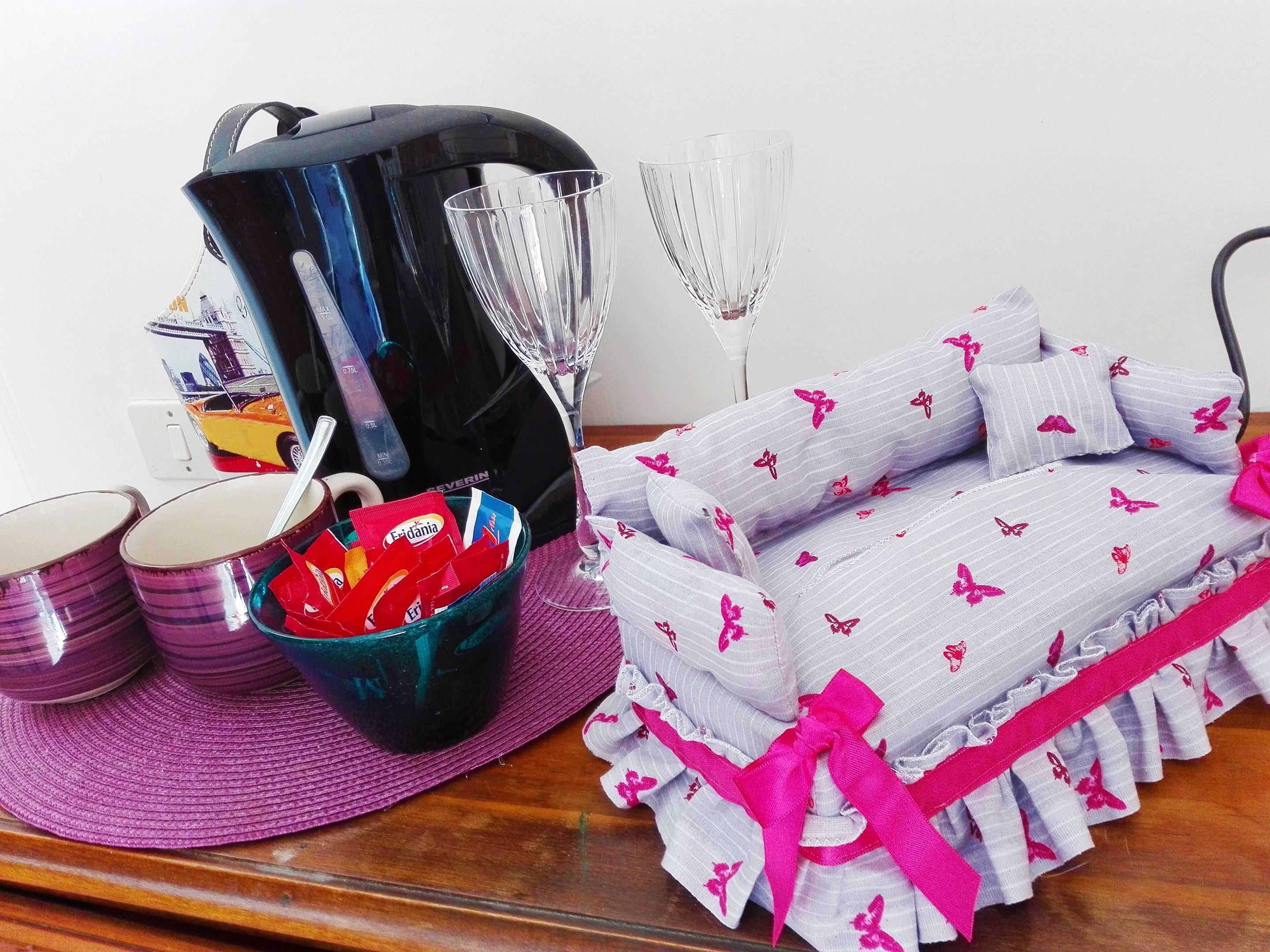 A kitchen area with a coffee maker, a glass, and a basket of items on a table.